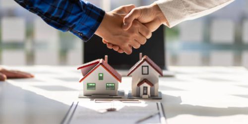 Real estate agents shake hands after the signing of the contract agreement is complete.